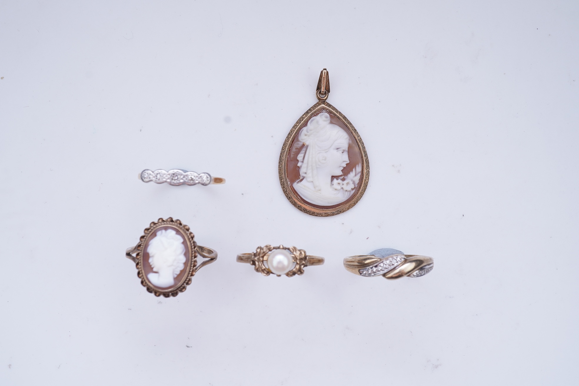 A collection of four rings and a pendant